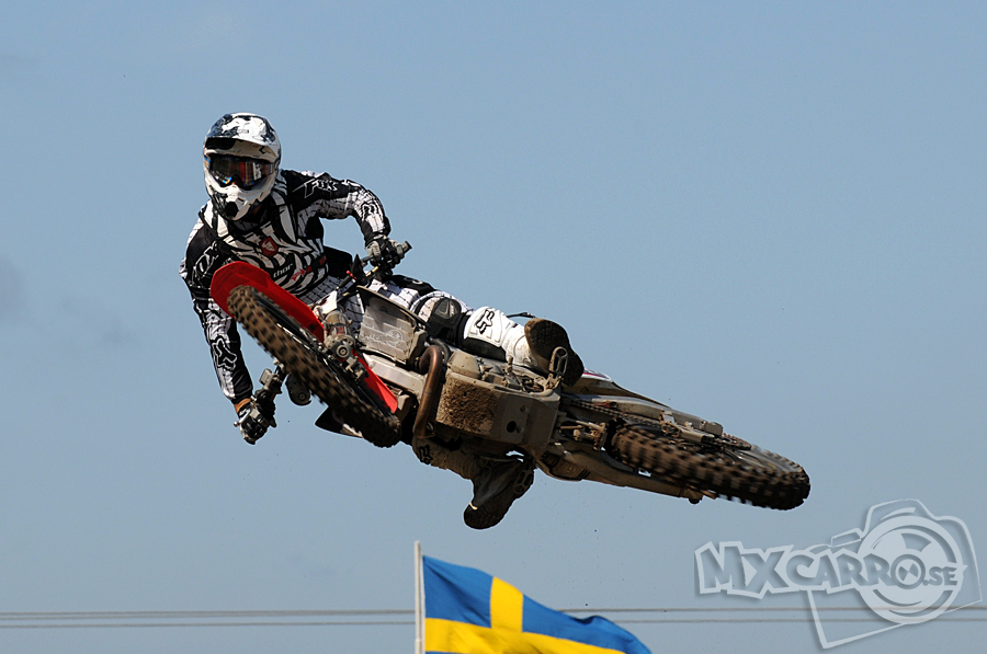 Svensk motocross, flaggan som visar det i bakgrunden och solen som värmer föraren.